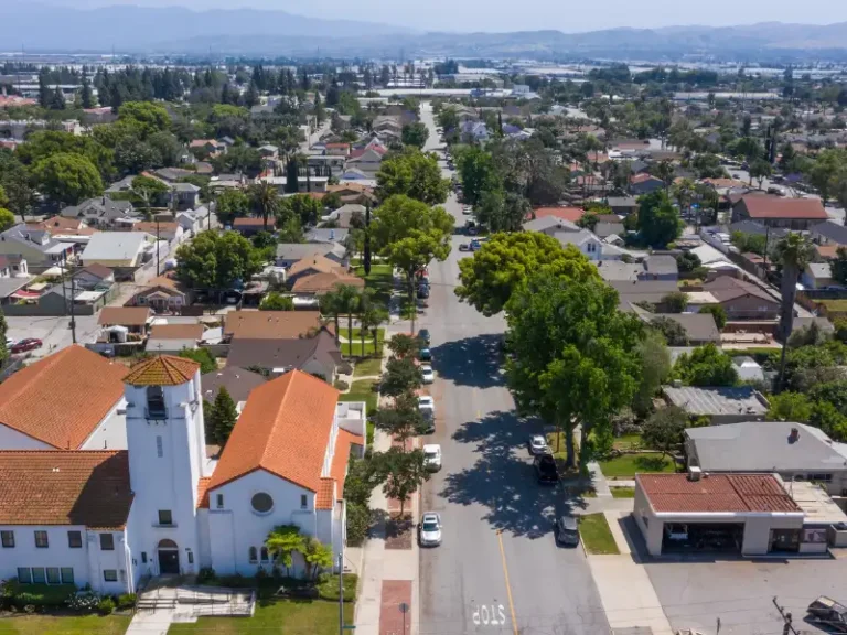 Aerial view of a suburban neighborhood with a church and tree-lined street.