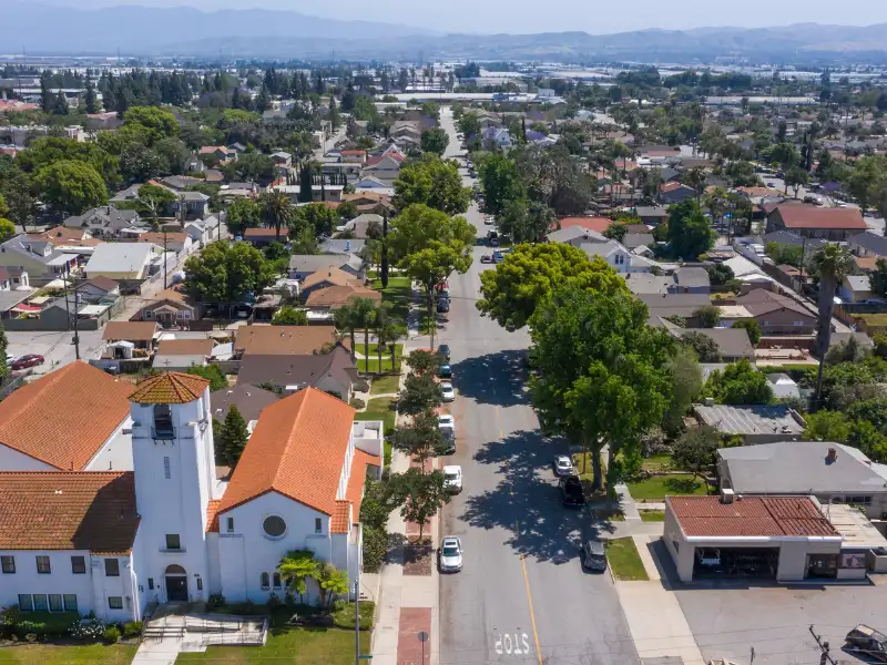 Aerial view of a suburban neighborhood with a church and tree-lined street.