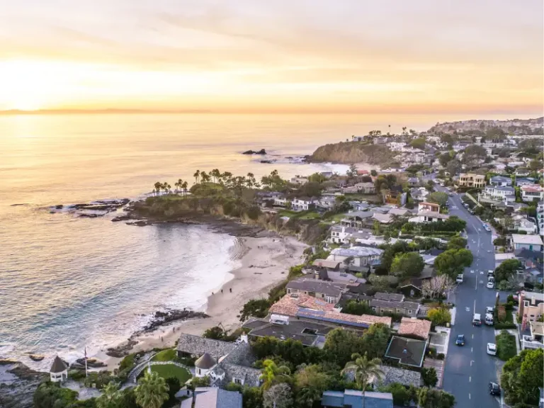 Coastal neighborhood with a beach and cliffs at sunset.