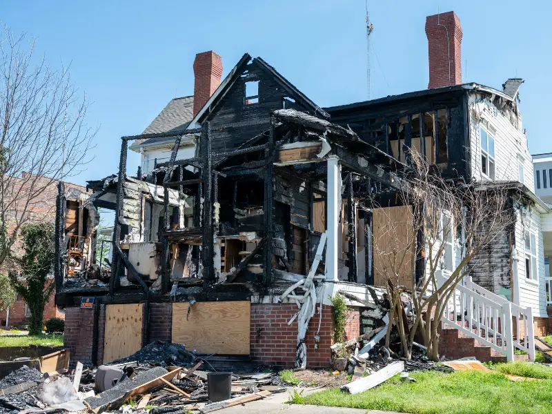 Burned-out house with severe fire damage and boarded windows.