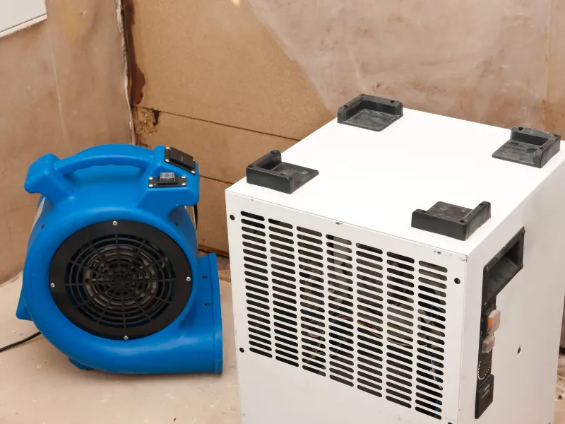 Blue blower fan beside a white air filtration unit.